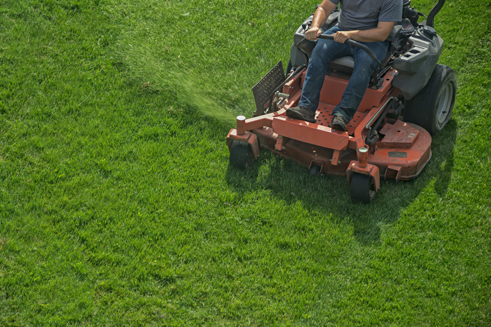 A landscape worker on a tractor mowing a large lawn in El Dorado, KS