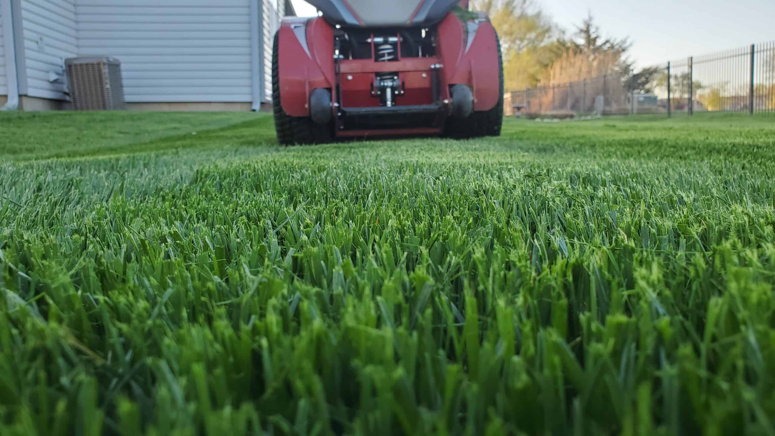 the back view of a riding lawnmower as it cuts grass in a large lawn