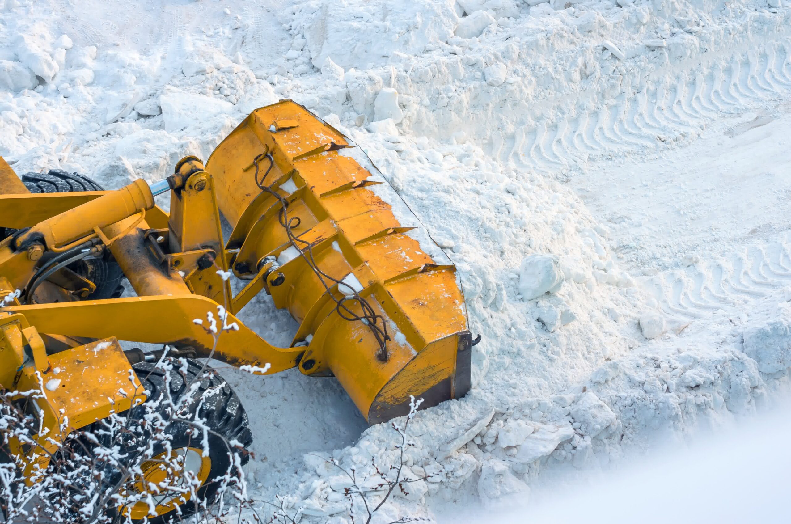 A piledriver removing a heap of snow from a road.