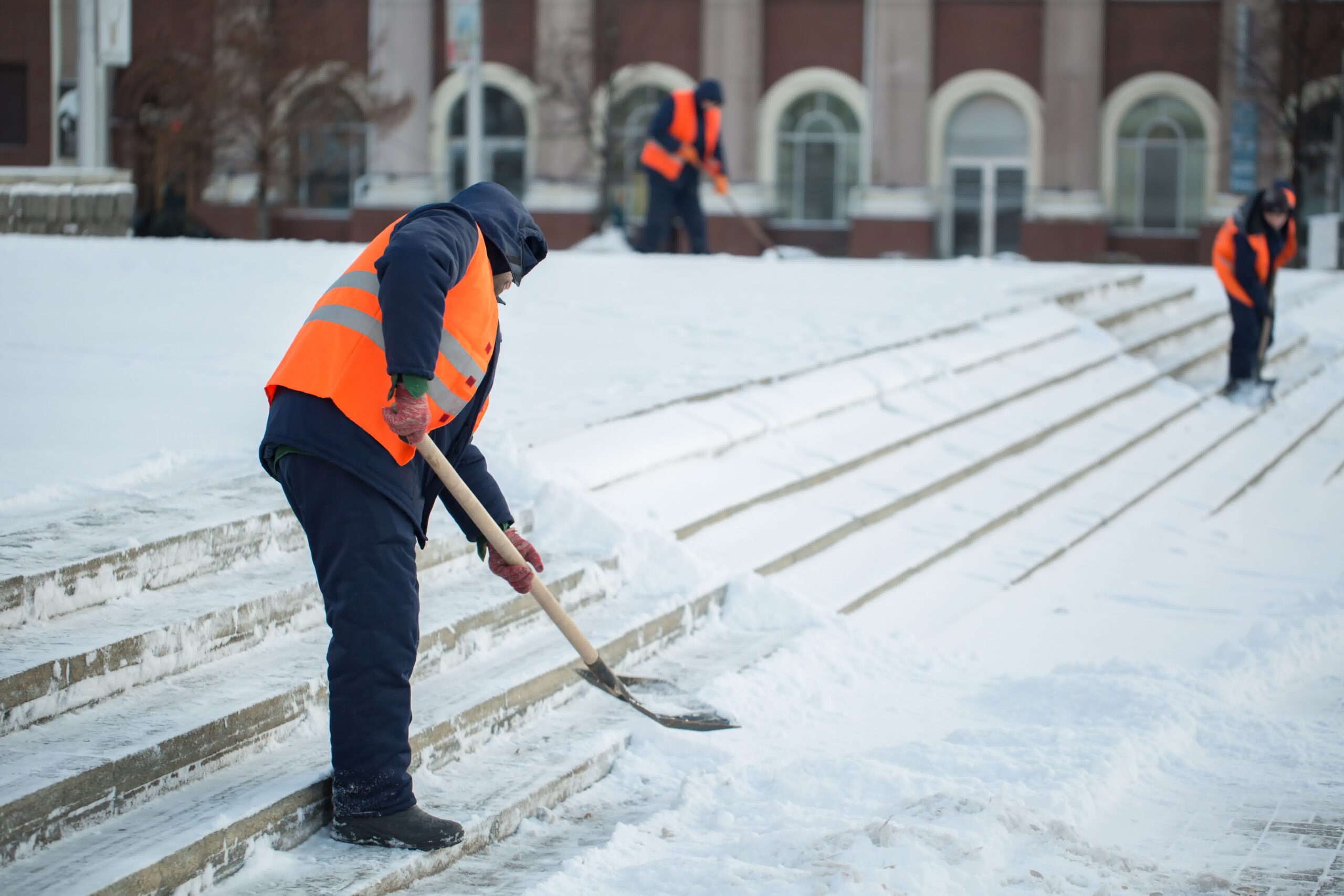 Three people shoveling snow with shovels.