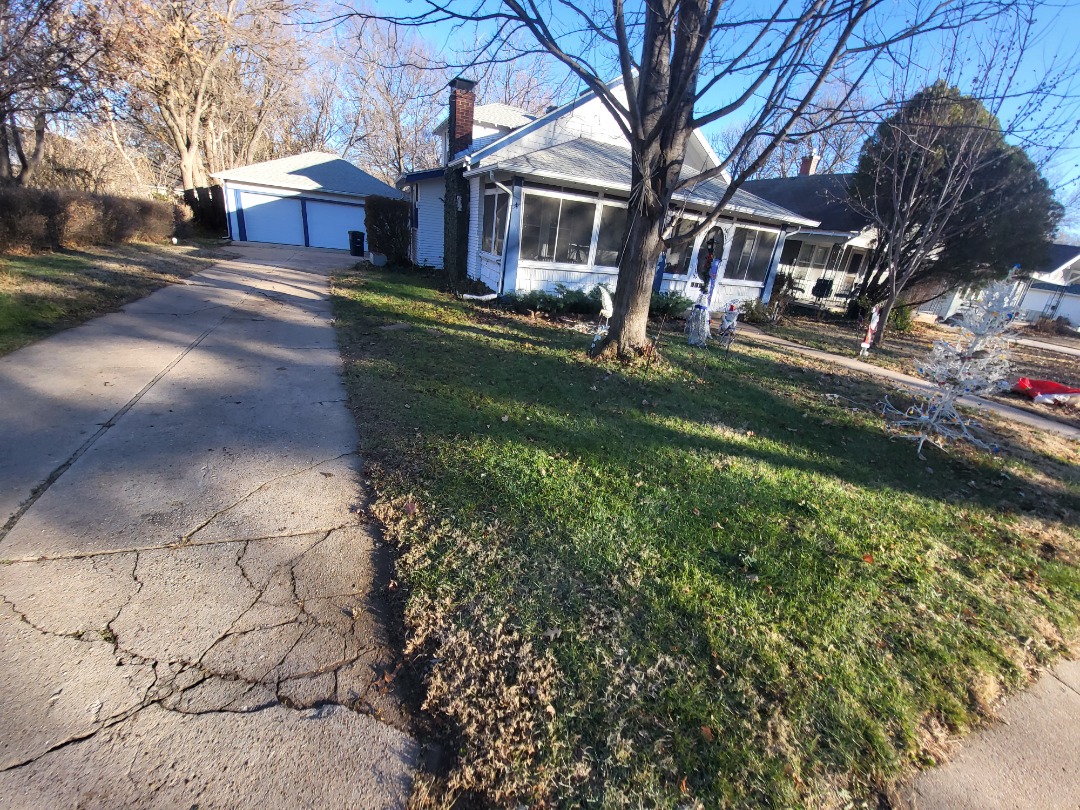 Residential lawn showing early spring care needs with patchy grass before professional lawn care treatment.